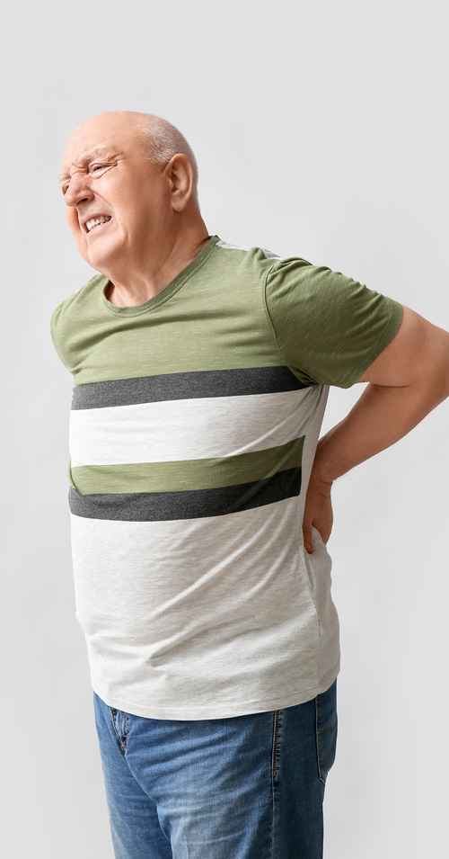 elderly man suffering from back pain wearing a green striped shirt demonstrating two common symptoms of discomfort