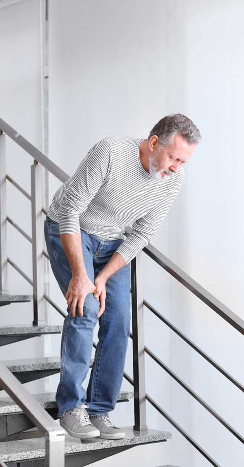elderly man experiencing knee pain on stairs demonstrating mobility issues and joint discomfort